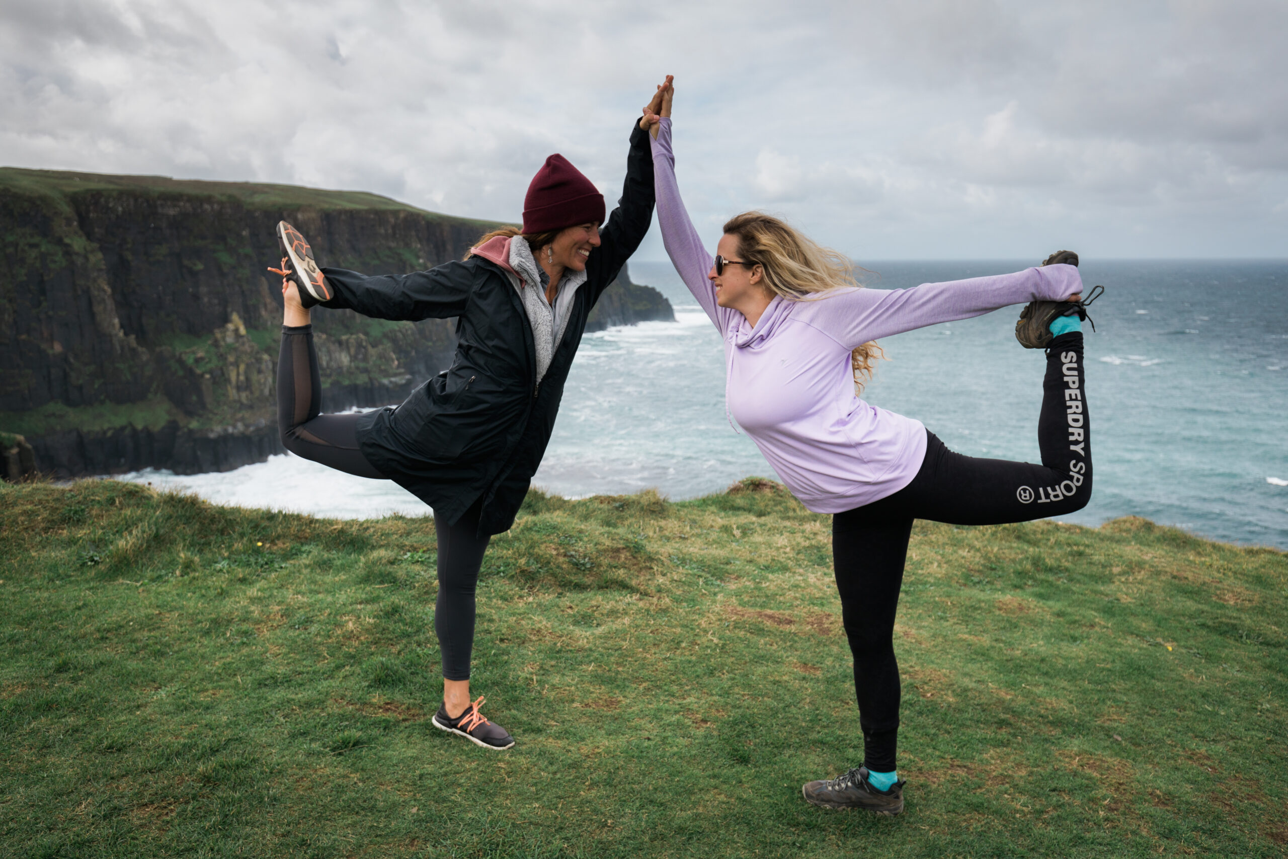 two ladies hiking yoga pose on cliffs